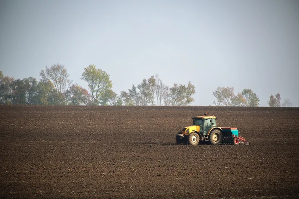 Фермер с тракторными посевами на поле — стоковое фото