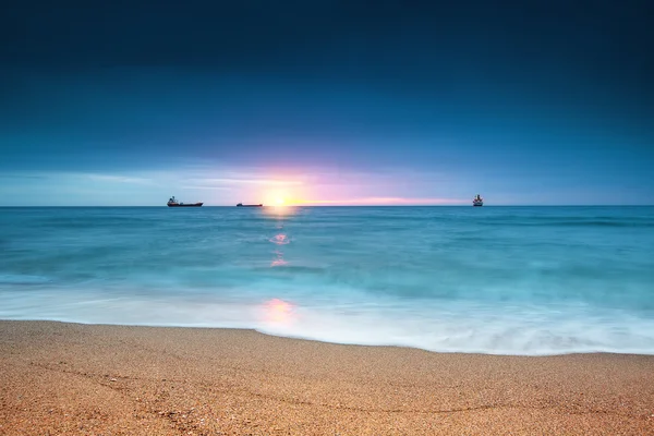 Cargo ship sailing on sunrise near the beach — Stock Photo, Image