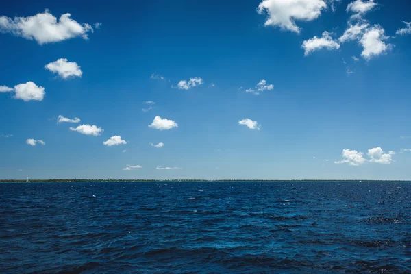Puszyste białe chmury niebieski niebo nad powierzchnią morza — Zdjęcie stockowe