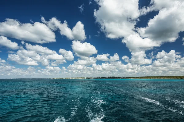 海の表面上に白いふわふわ雲の青い空 — ストック写真