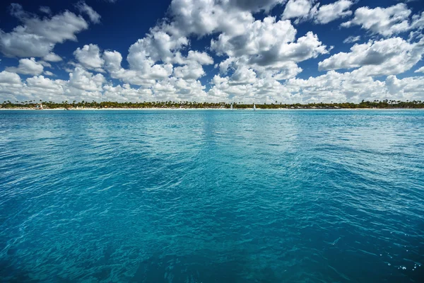 Nuages blancs moelleux ciel bleu au-dessus d'une surface de la mer — Photo