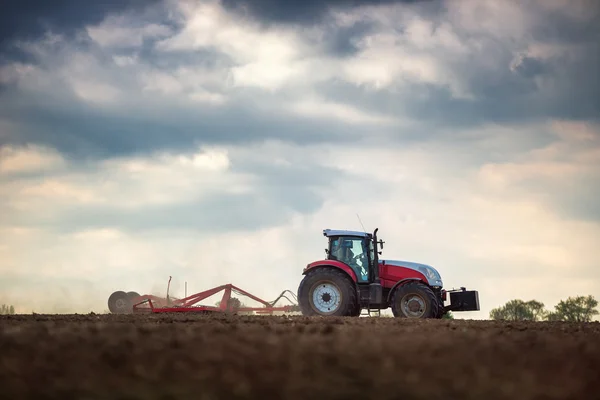 Agricultor en tractor preparando tierra con cultivador de semillero —  Fotos de Stock