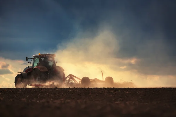 Agricultor en tractor preparando tierra con cultivador de semillero —  Fotos de Stock