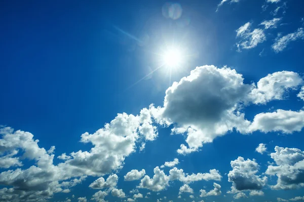 Beau ciel bleu avec des nuages blancs pelucheux et le soleil — Photo