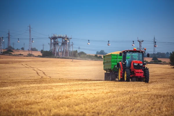 Agricoltore che guida trattore agricolo e rimorchio pieno di grano — Foto Stock