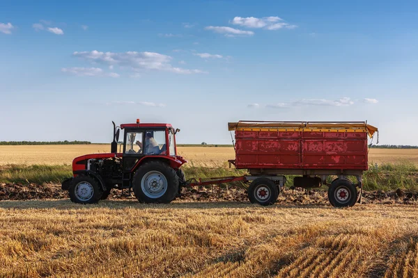 Trator vermelho com reboque vermelho ina campo — Fotografia de Stock