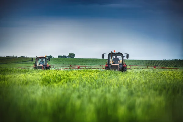 Plantação de tratores agrícolas e pulverização no campo — Fotografia de Stock