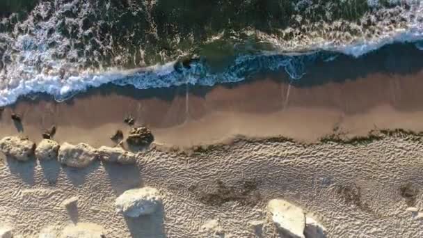 Vista aérea de olas, mar y playa de arena. La perspectiva es recta hacia abajo . — Vídeos de Stock