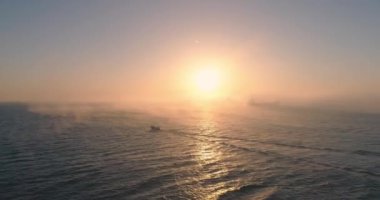 Deniz doğumu, uçan martılar ve sisli bir sabahta kargo gemisiyle karşı karşıya gelmek. Hava 4K videosu