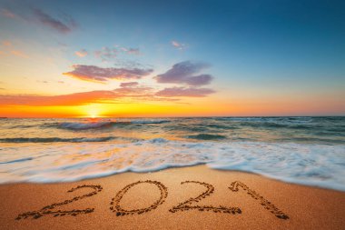 Mutlu yıllar 2021 konsepti, plajda yazı yazmak. Gün doğumunda sahilde yazılmış bir metin..