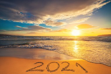 Mutlu yıllar 2021 konsepti, plajda yazı yazmak. Gün doğumunda sahilde yazılmış bir metin..