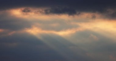 Gün doğumu. Güneş ışınları hareket eden dramatik beyaz bulutlarda parlıyor. Bulutlu mavi günbatımı gökyüzü, 4k video