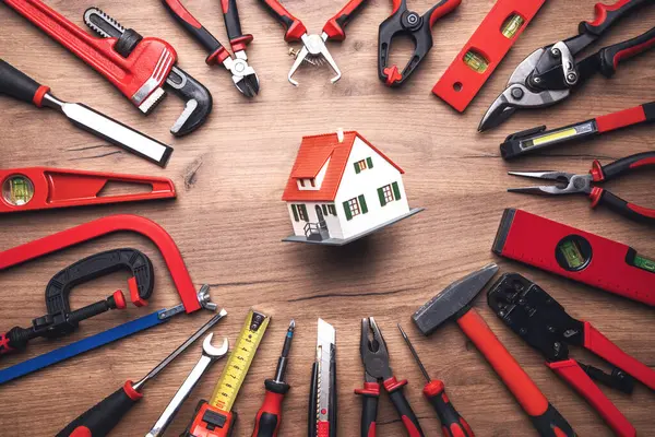 Ahşap arka planda çeşitli iş araçları ve ev