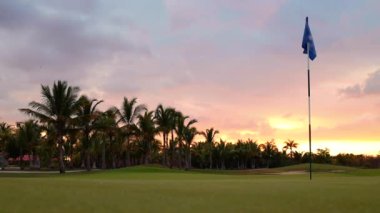 Lüks tropikal tatil köyündeki golf sahasında. Spor sahalarında, bahçelerde ve palmiyelerde gün batımı