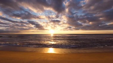 Deniz doğuyor ve dalgalar kumlara vuruyor.