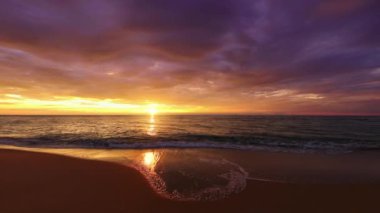 Güneş doğarken tropik plaj ve okyanus. Okyanus dalgaları kuma vuruyor..
