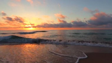 Güneş doğarken tropik plaj ve okyanus. Okyanus dalgaları kuma vuruyor..