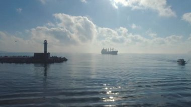 Denizde deniz feneri ve sakin sularda yelkenli gemi ve tekne, 4K video.