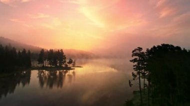 Dağ gölünün üzerinde sabah sisi, güneşin doğuşu 4k hava manzarası.