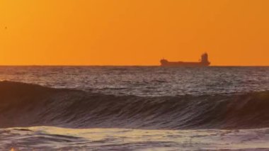 Fırtınalı okyanus dalgalarıyla gün doğumunda kargo gemisine bineceğiz.