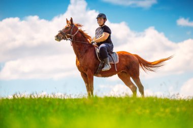 Genç çocuk tarlada ata biniyor.