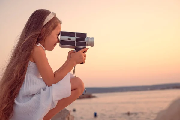 レトロカメラで海の夕日とビーチを楽しむ幸せな女の子 — ストック写真