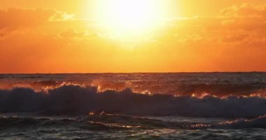 Deniz dalgaları ve sahilde renkli gün doğumu ya da gün batımı. 4k ağır çekim videosu