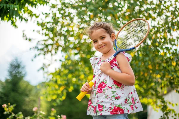 Retrato de una niña sonriente sosteniendo raqueta de tenis — Foto de Stock