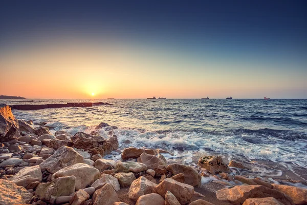 Tropiska färgglada soluppgången vid stenarna stranden. — Stockfoto