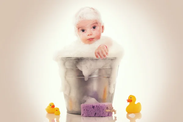 Pequeno bebê em um balde no fundo branco — Fotografia de Stock