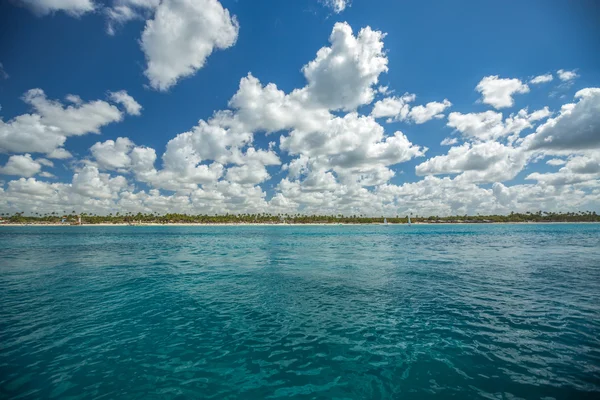 Nuages blancs moelleux ciel bleu au-dessus d'une surface de la mer — Photo