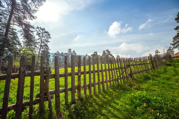 Забор в зеленом поле под голубым небом облака — стоковое фото