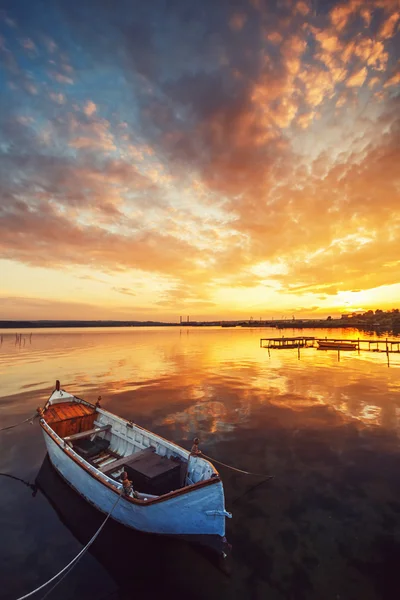 Hermosa puesta de sol sobre el lago tranquilo y un barco con el cielo que refleja i — Foto de Stock