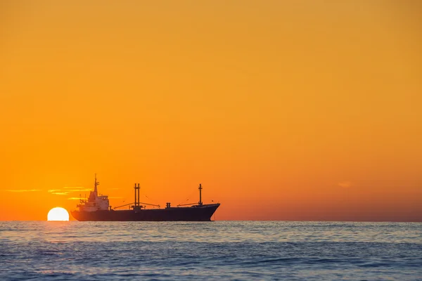 Вантажний корабель, що пливе на сході сонця біля морської гавані — стокове фото