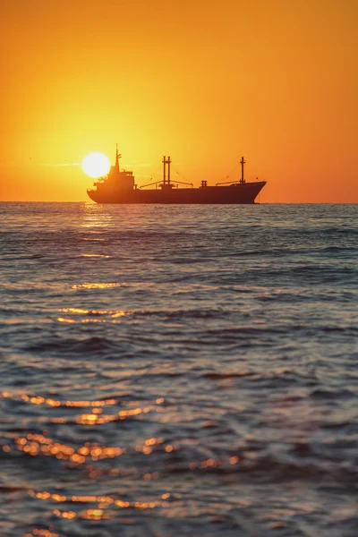 Вантажний корабель, що пливе на красивому сході сонця біля морської гавані — стокове фото