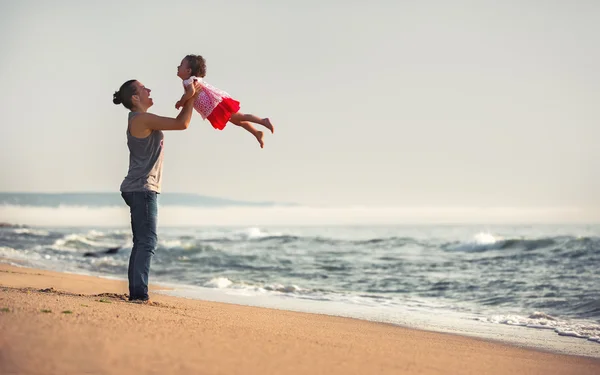 Madre y bebé jugando en la playa al atardecer — Foto de Stock