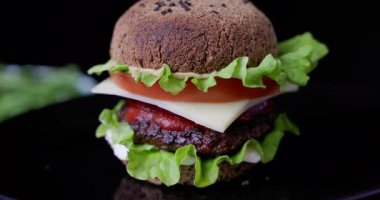 Sağlıklı sığır eti sulu burger ve marul peynirli keto ekmeği öğle yemeği için glütensiz keto ekmeği ya da siyah arka planda 360 derecelik video ile akşam yemeği.