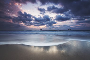 Denizin üzerinde dramatik bulutlar, güneşin doğuşu.