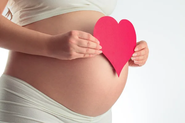 Brzuch kobiety w ciąży i czerwonym sercem na biały — Zdjęcie stockowe
