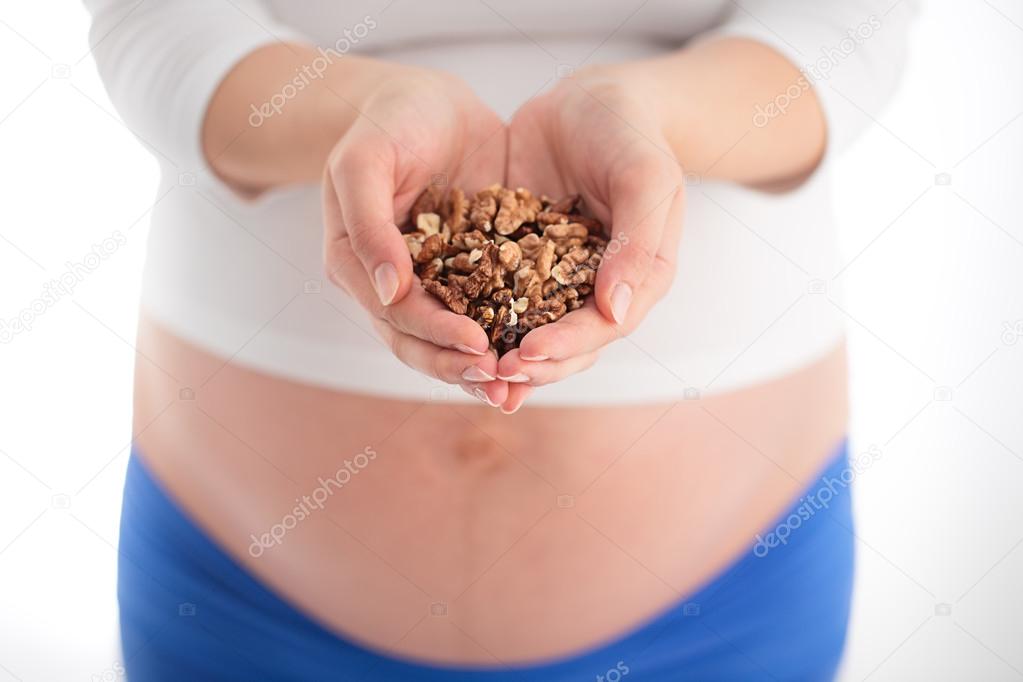 Pregnancy and healthy daily menu - pregnant woman with nuts in h