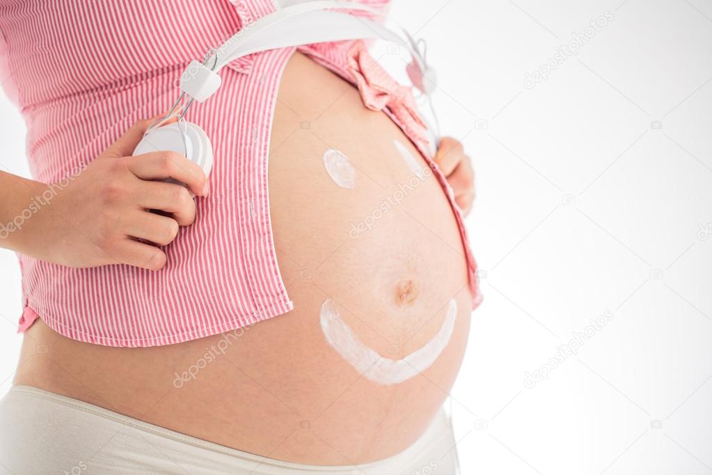 Music and pregnancy concept. Pregnant woman belly with smiley fa