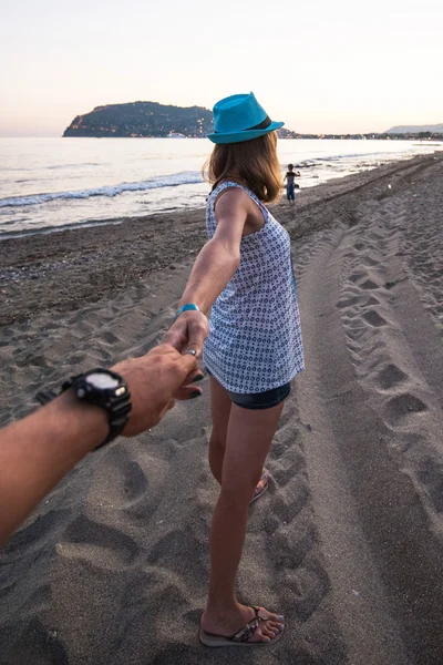 Flicka som håller en hand man på stranden — Stockfoto