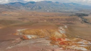 Mars 'ın yüzeyine benzeyen dokulu sarı ve kırmızı dağların havadan çekilmiş videosu.