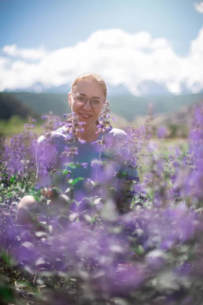 Gelukkige jonge vrouw in mooie wilde roze en paarse bloemen veld — Stockfoto