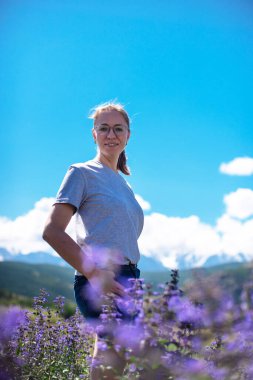 Güzel, pembe ve mor çiçek tarlasında mutlu bir genç kadın.