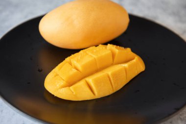 Siyah tabakta taze sarı mango meyvesi.