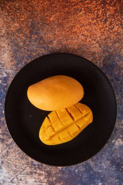 Siyah tabakta taze sarı mango meyvesi.