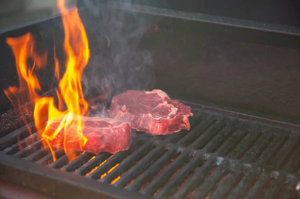 Beef steaks on the grill with flames — Stock Photo, Image