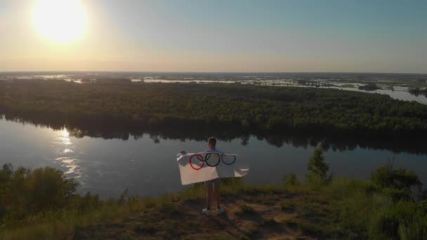Niño rubio ondeando bandera nacional de EE.UU. al aire libre sobre el cielo azul en la orilla del río — Vídeos de Stock