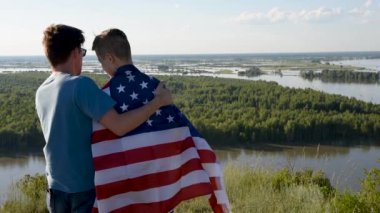 Sevimli genç bir çocuk ve babası Amerikan bayrağını havada tutuyorlar.